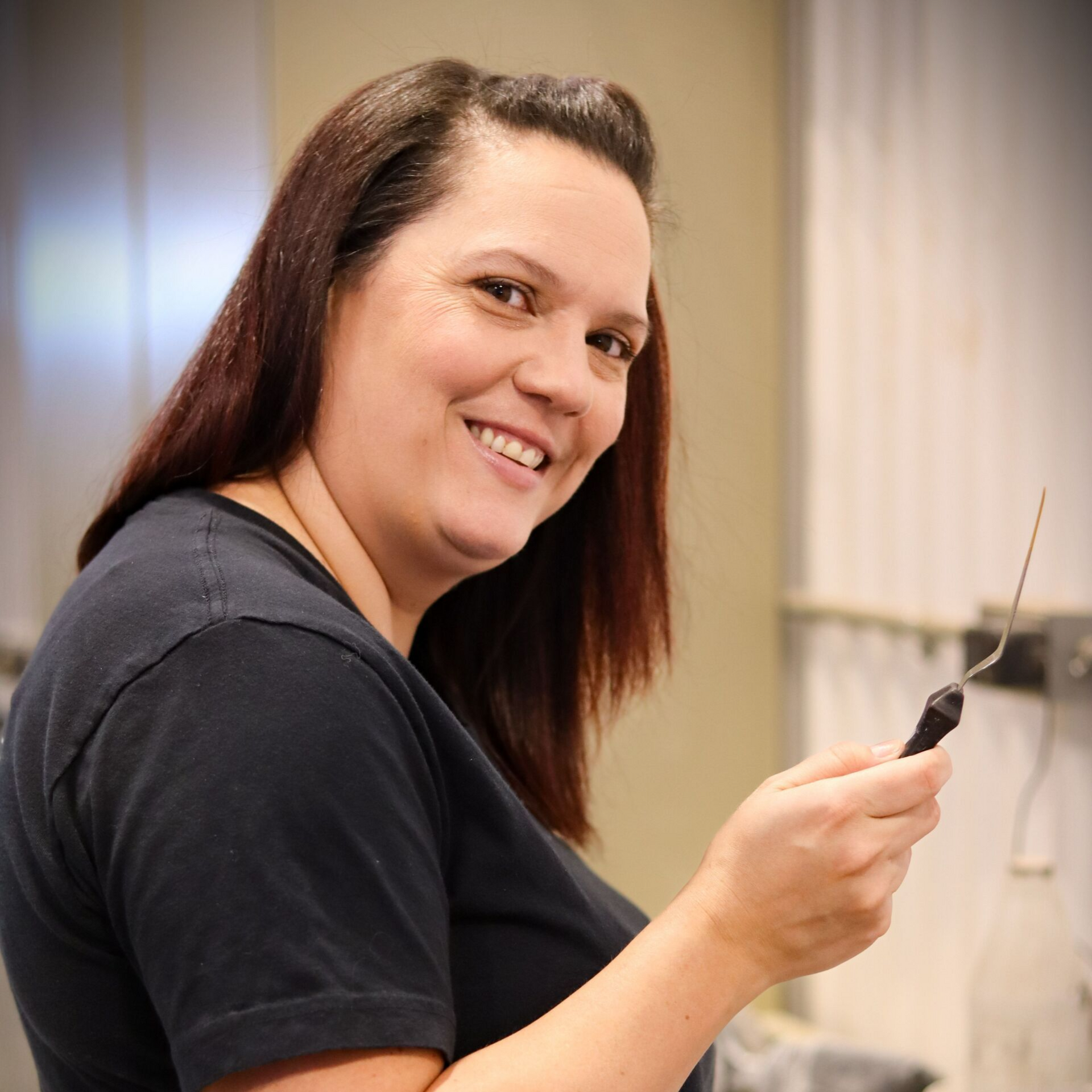 Femme souriante, tenant un outil muni d'une fine sonde métallique, à l'intérieur.