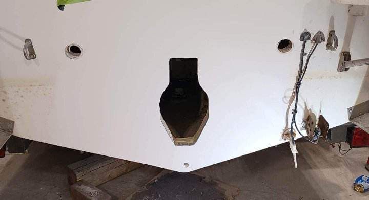 Tableau arrière de bateau blanc avec une grande ouverture, plusieurs trous et câblage.