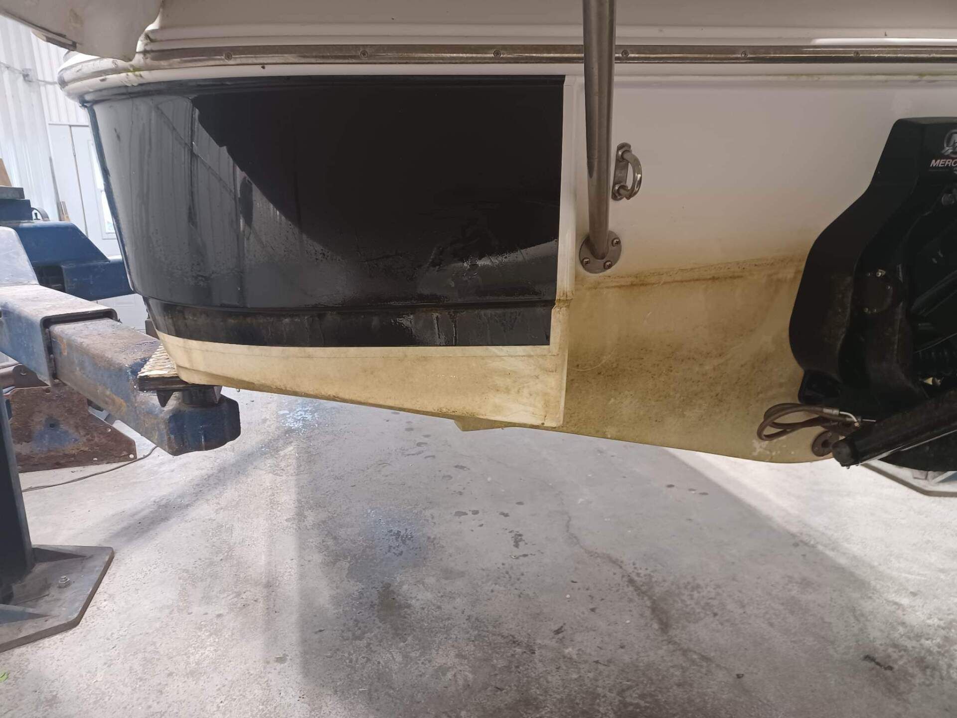 La poupe d'un bateau, avec sa peinture antifouling noire et sa partie inférieure jaunie et sale, sur un élévateur à bateaux.