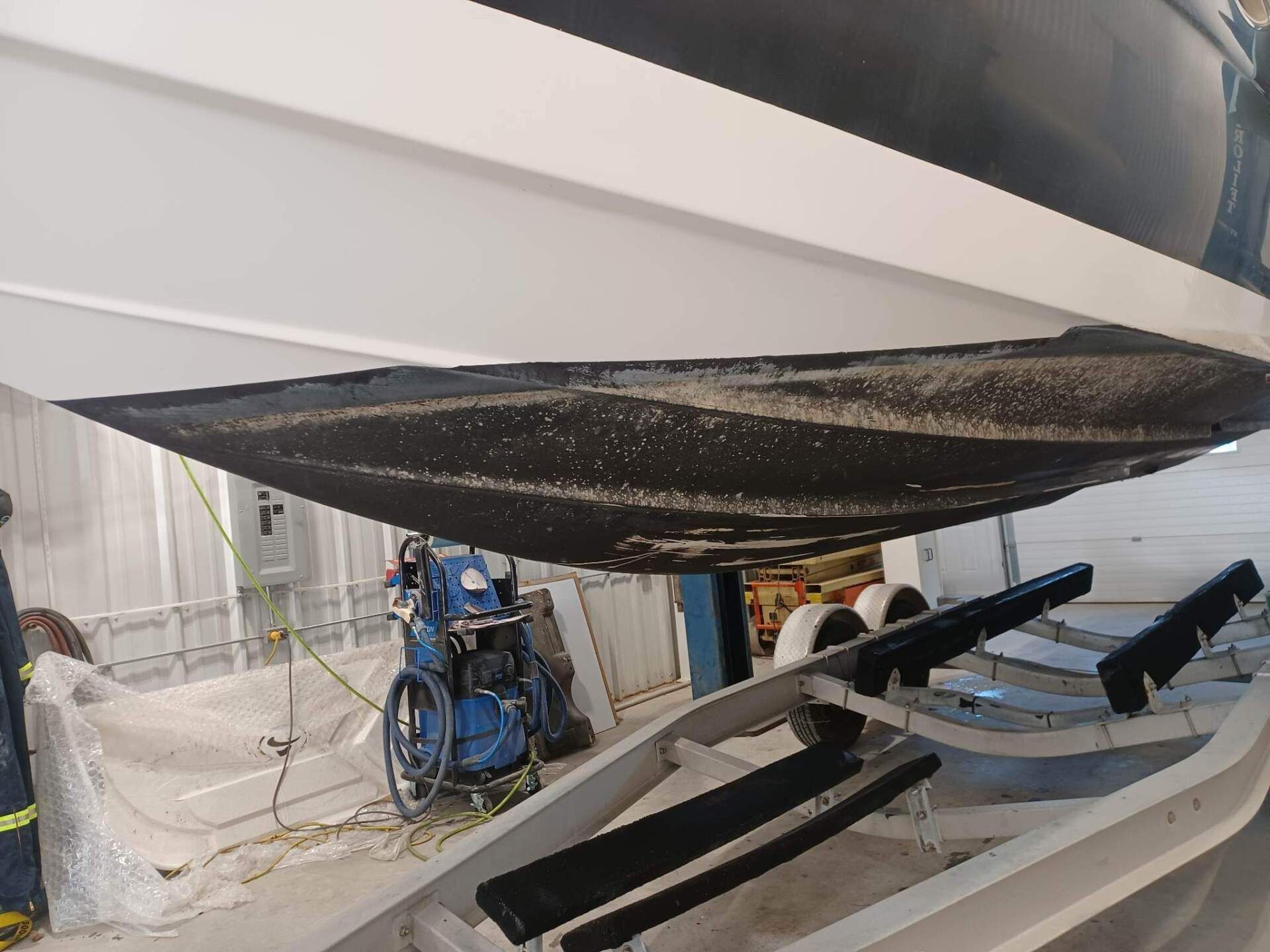 Dessous du bateau, revêtement noir, reposant sur une remorque, configuration intérieure.