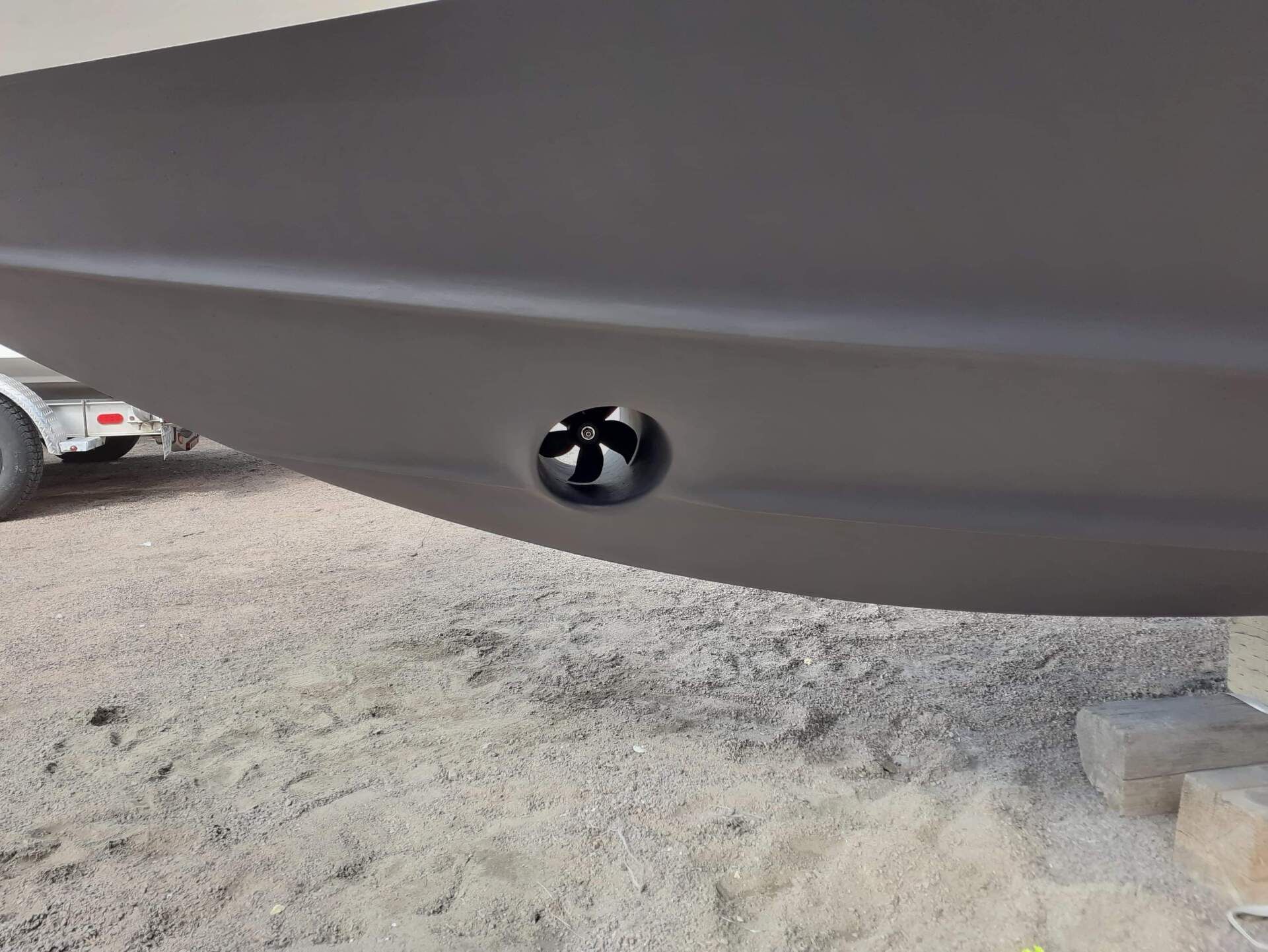 Propulseur d'étrave noir sur la coque grise d'un bateau, vue rapprochée.