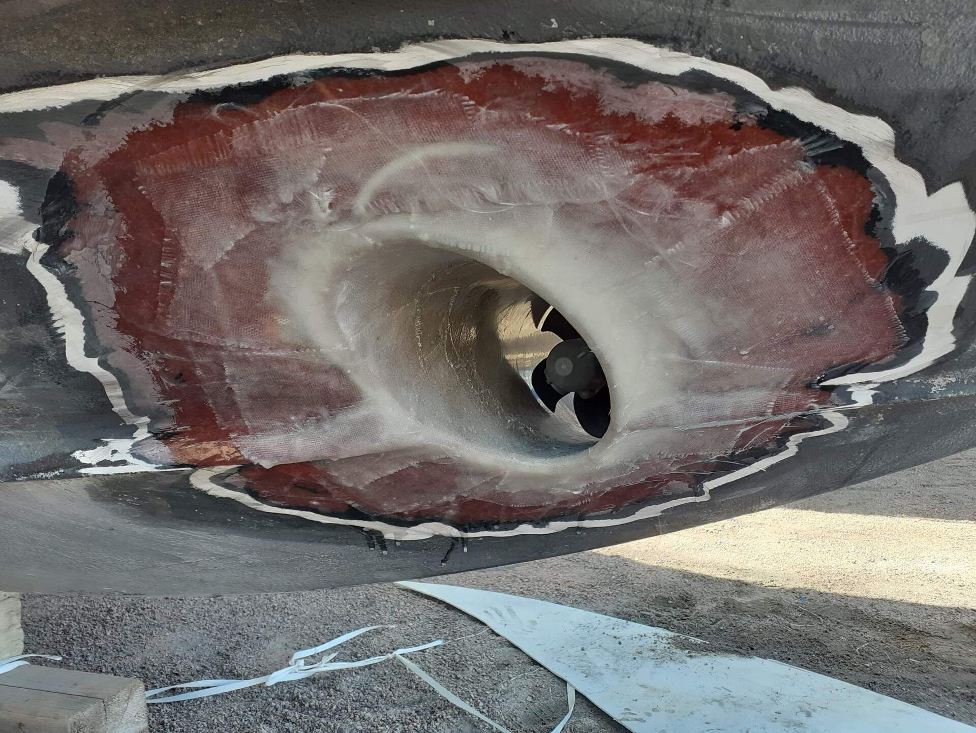 Trou dans la coque d'un navire, colmaté avec de la résine rouge et du mastic blanc, probablement pour un arbre d'hélice.