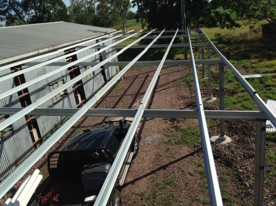 A Car Is Parked Under A Metal Structure In Front Of A Building — LJG Plumbing In Sarina, QLD