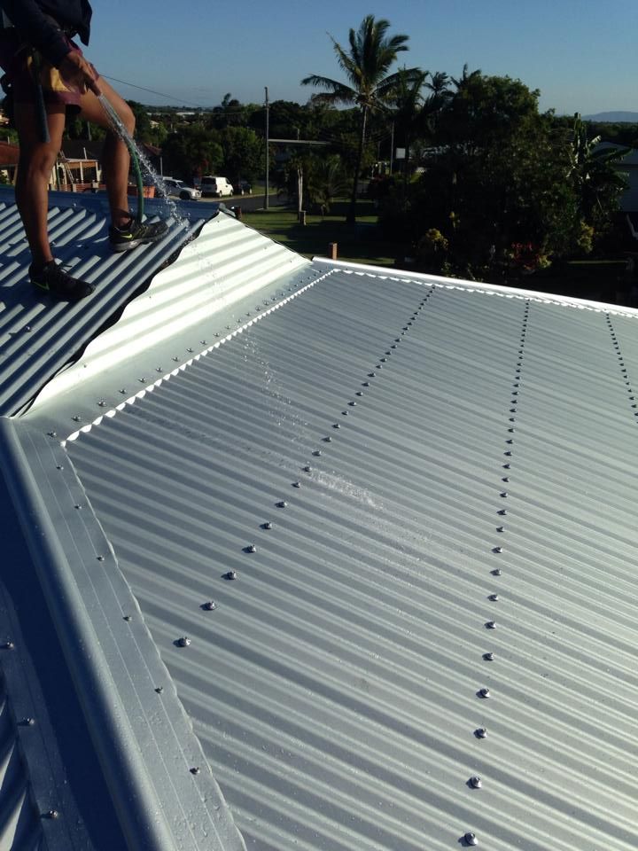 A Person on a metal roof securing the edges — LJG Plumbing In Sarina, QLD