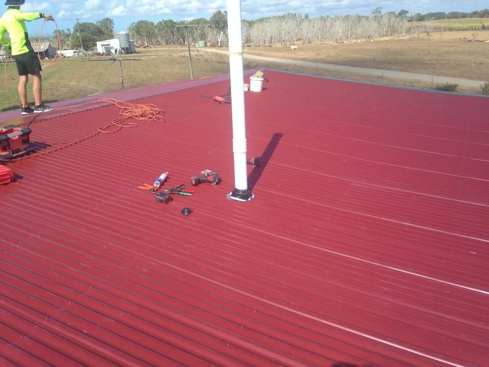 A Person on a Red Corrugated Metal Roof — LJG Plumbing In Sarina, QLD