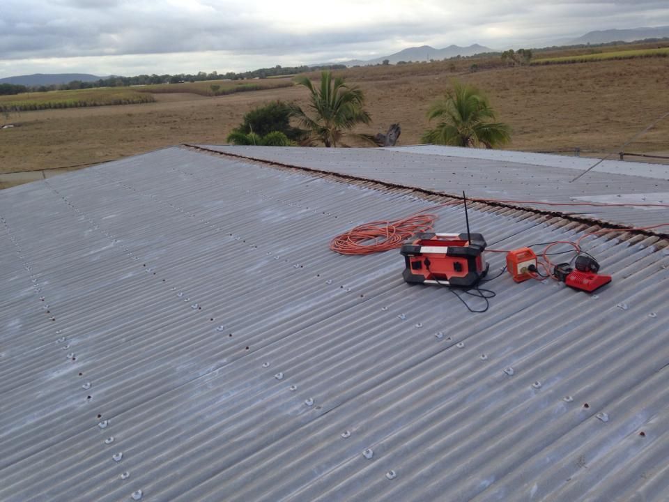 Gray Corrugated Metal Roof With Orange Equipment — LJG Plumbing In Sarina, QLD