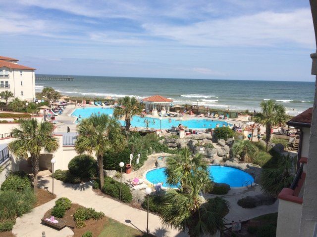 An aerial view of a resort with a large pool and palm trees