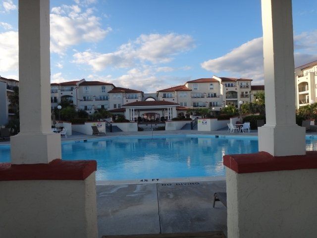 A large swimming pool is surrounded by a row of buildings