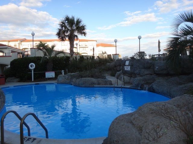 A large swimming pool is surrounded by rocks and palm trees