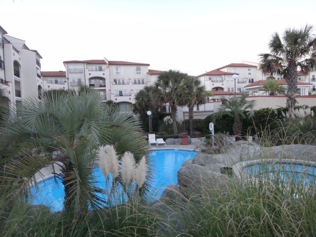 A large swimming pool surrounded by palm trees in front of a building