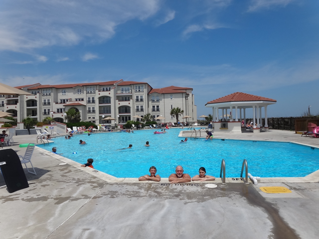 People are swimming in a large pool in front of a large building