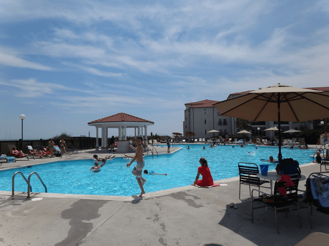 A man is jumping into a large swimming pool