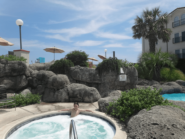 A young boy is laying in a hot tub surrounded by rocks