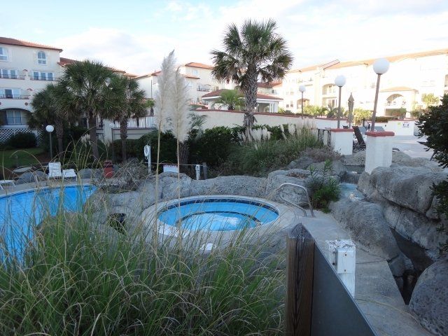 A swimming pool with a hot tub in the middle of it