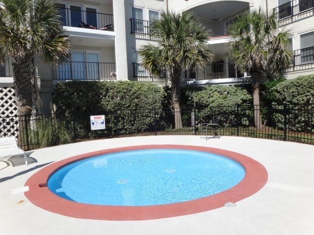 A small swimming pool in front of a building with palm trees