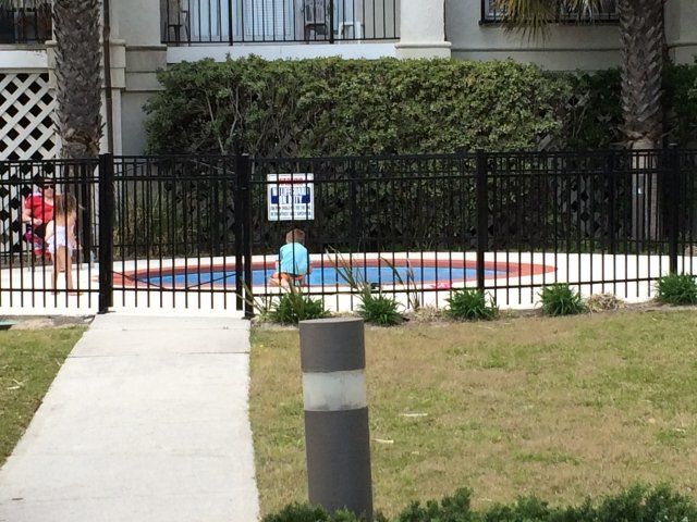 A fence surrounds a swimming pool with a sign that says no diving