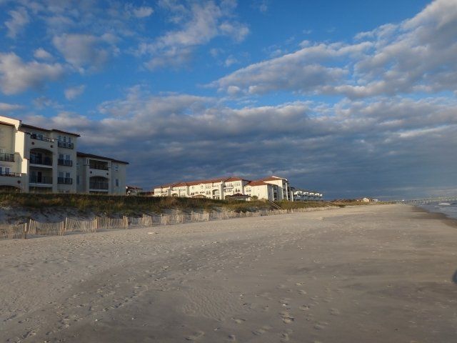 A beach with buildings in the background and a cloudy sky