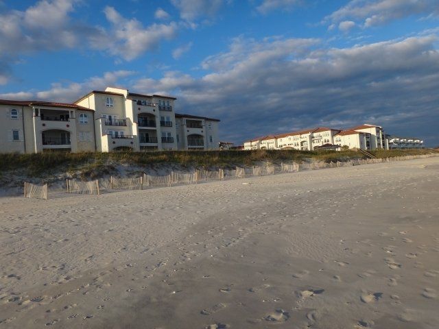 A row of buildings on a beach with a cloudy sky in the background