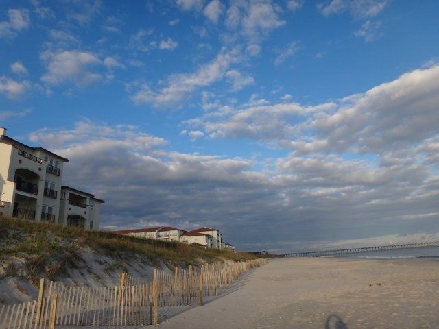 A beach with a fence and a house in the background
