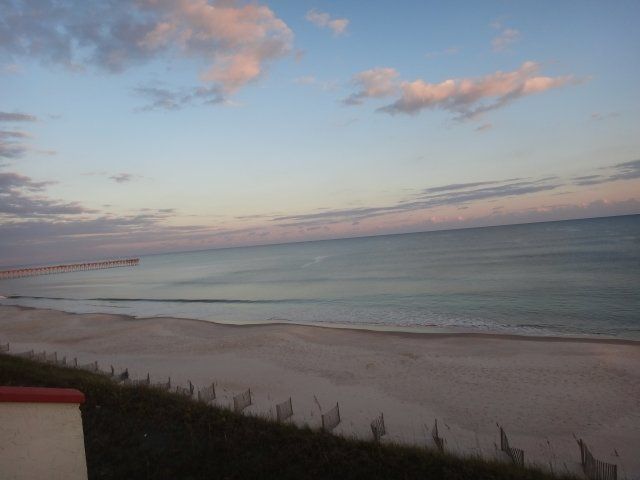 A view of a beach with a fence in the foreground