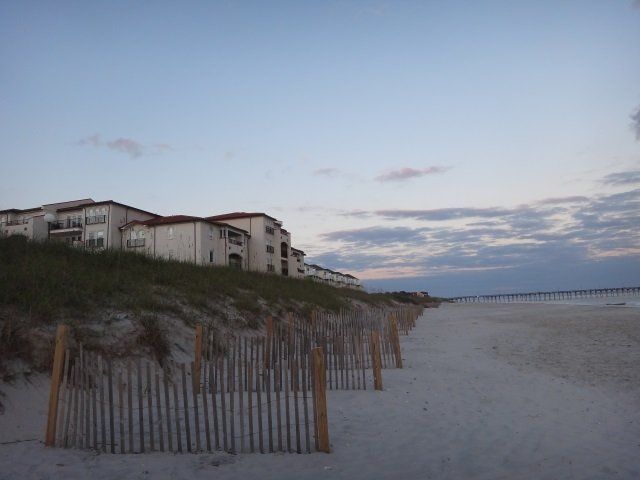 A beach with a fence and buildings in the background