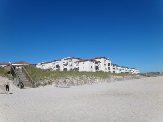 A large white building is sitting on top of a sandy beach.