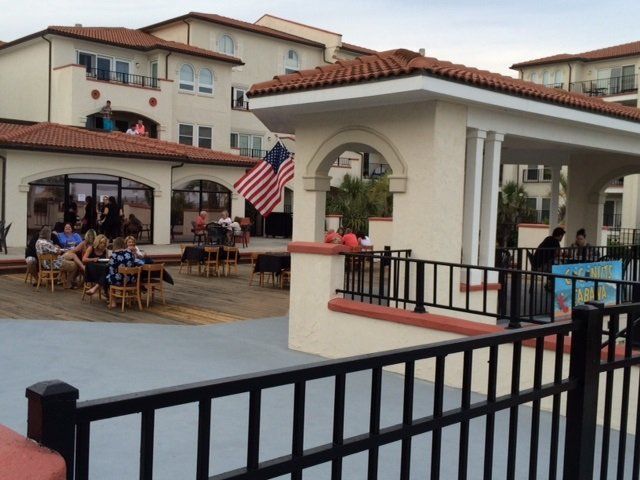 A group of people sitting at tables in front of a building with an american flag
