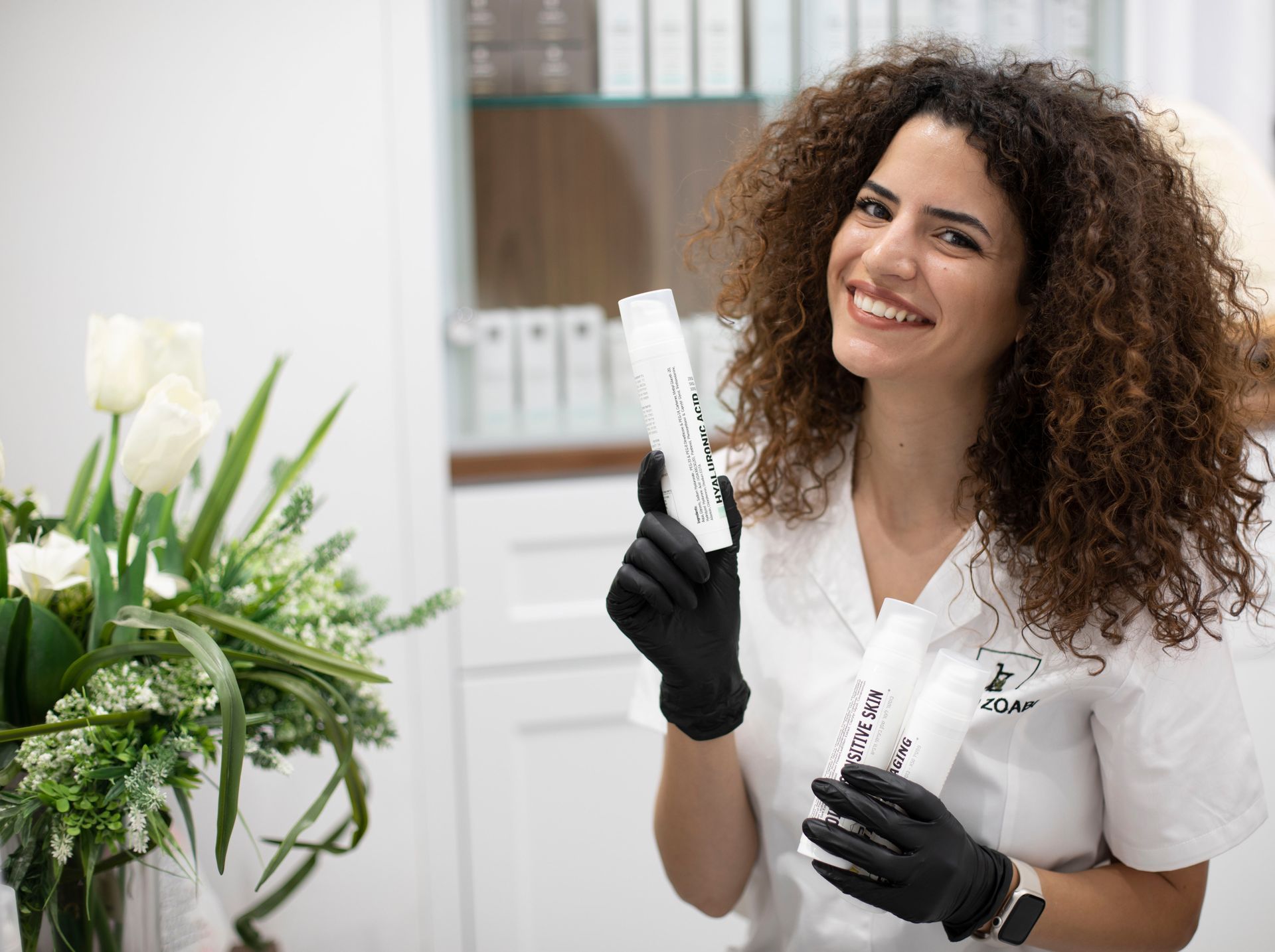 Eine Frau mit lockigem Haar hält eine Flasche Lotion und lächelt.