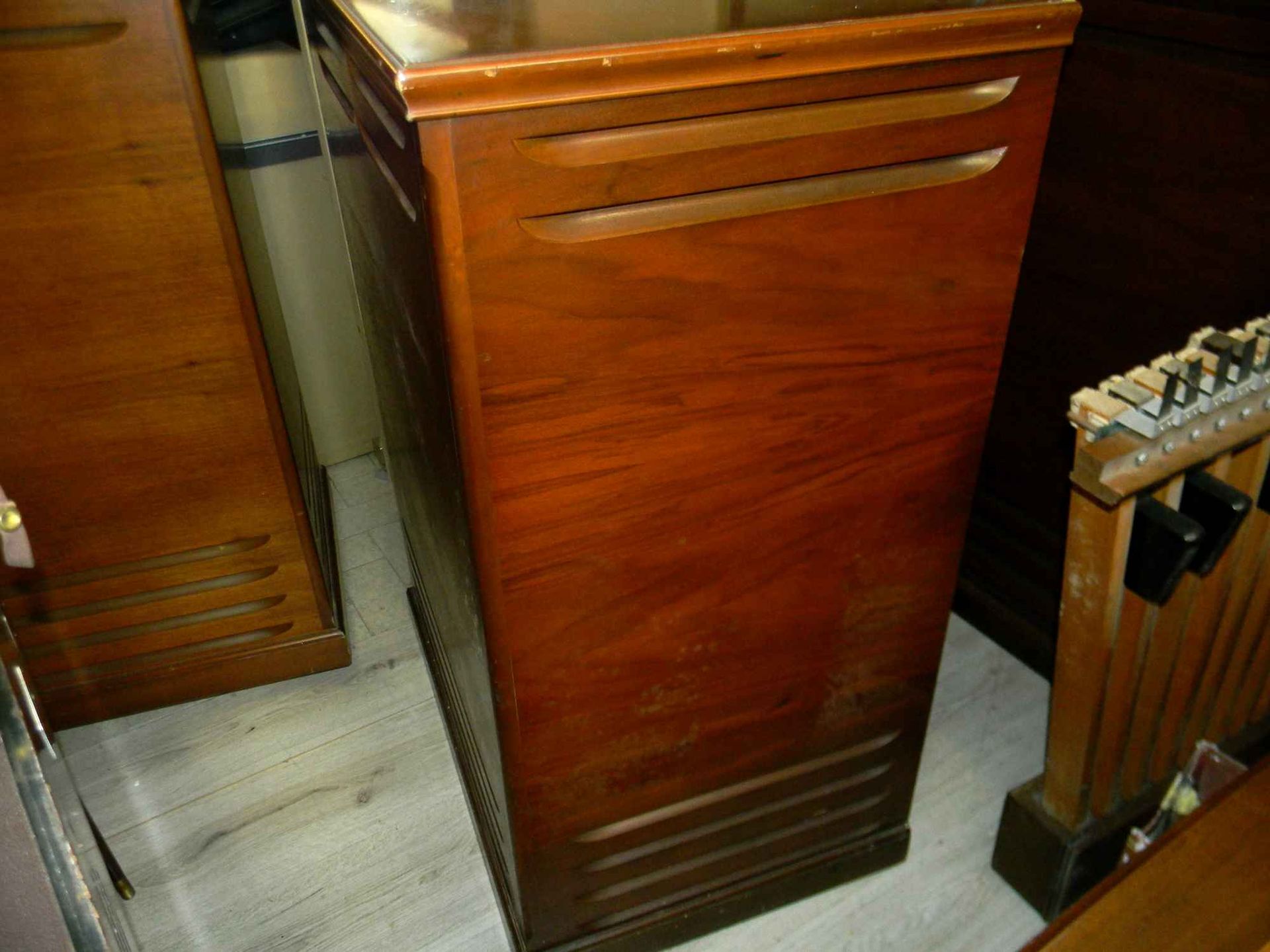 Wooden cabinet with horizontal vents, likely part of an organ or similar furniture.