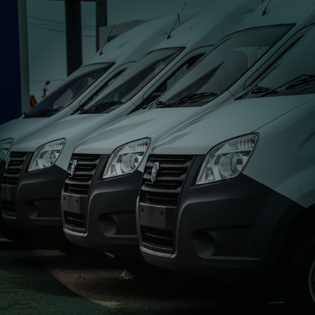 Uma fileira de vans brancas estão estacionadas uma ao lado da outra