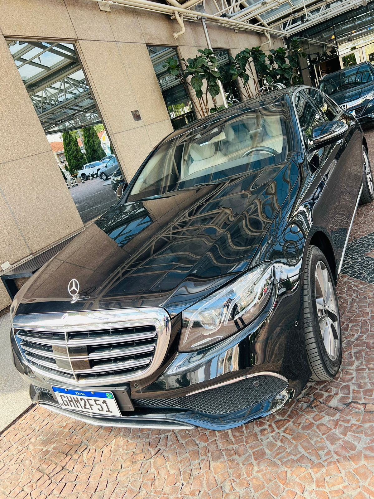 Um mercedes benz preto está estacionado em frente a um prédio.