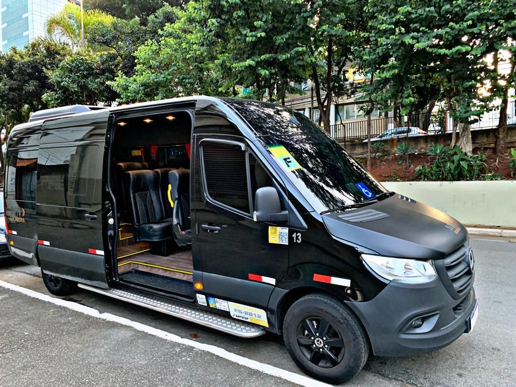 Uma van preta está estacionada na beira da estrada com as portas abertas.