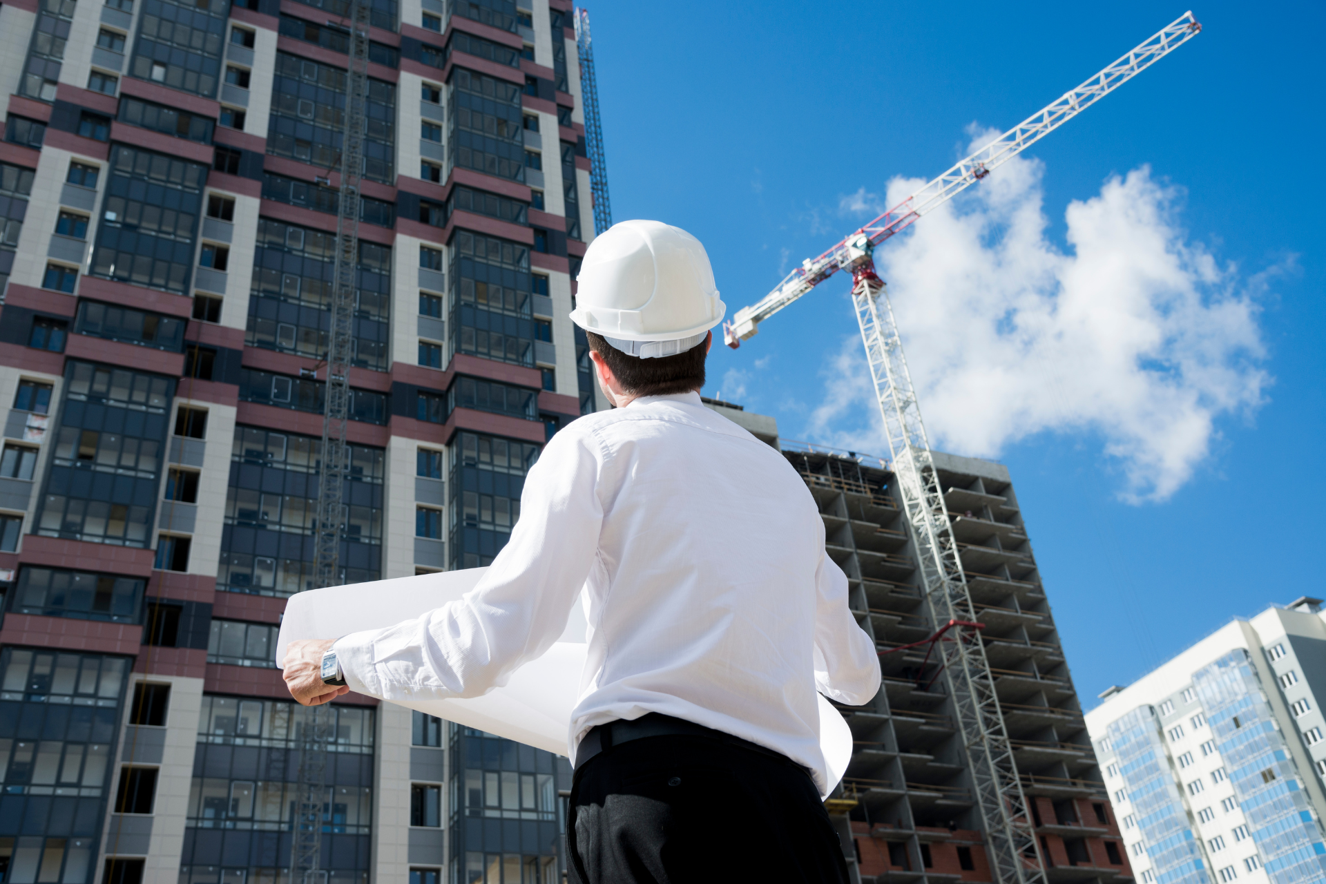 Construction worker in hard hat looking at blueprints at a construction site.