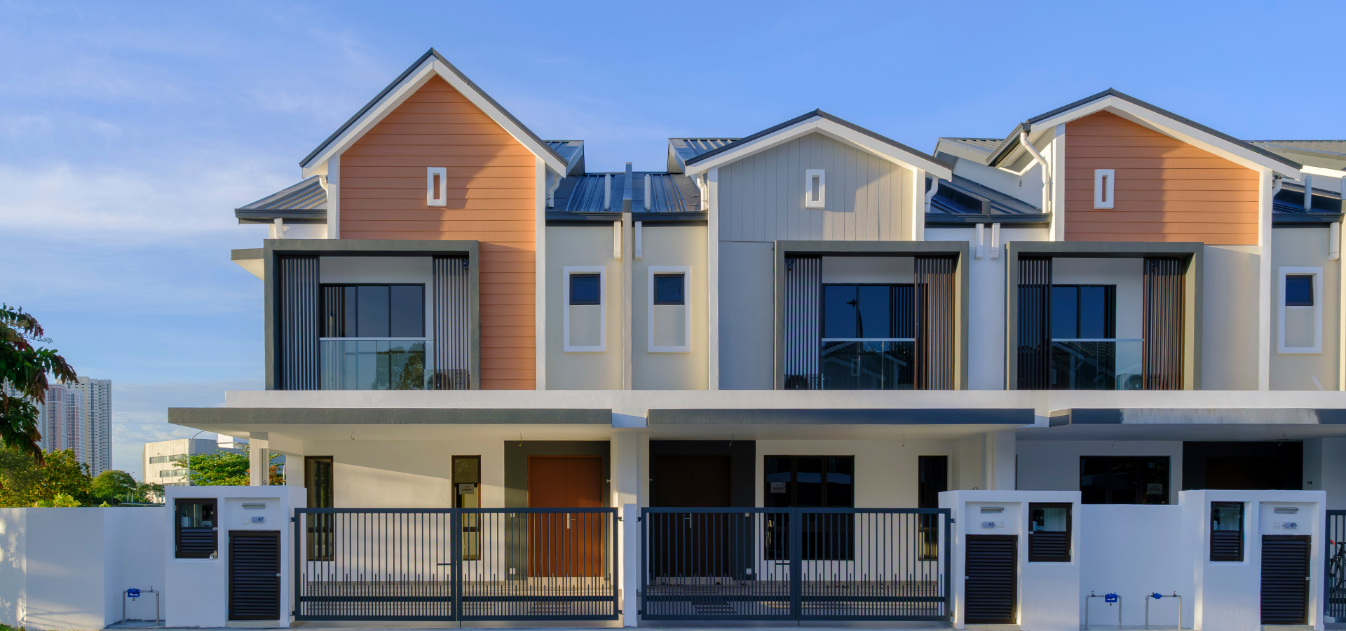 Modern two-story row houses with balconies, gray and peach facades, and a gated front entrance