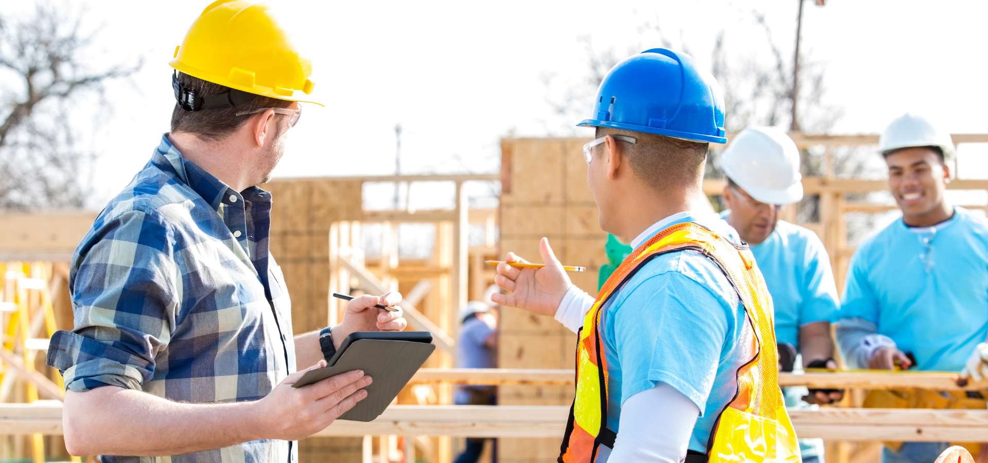 Construction workers in hard hats discussing plans at a building site