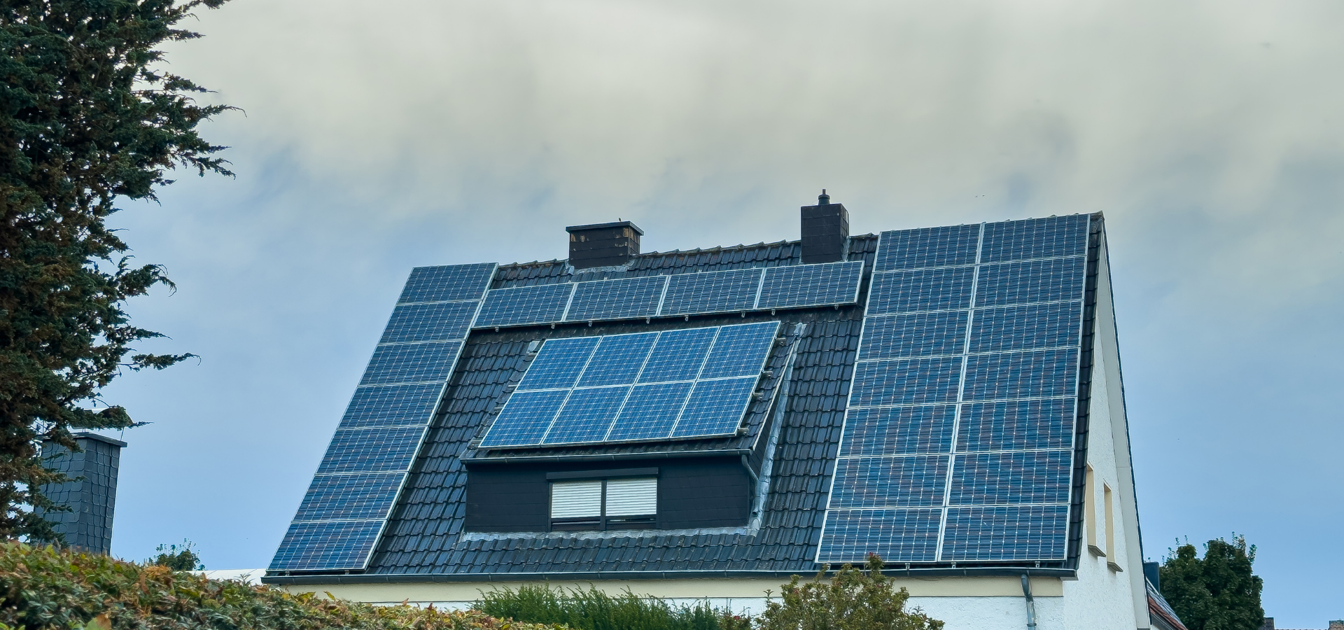 House with blue solar panels on a sloped roof under a clear sky