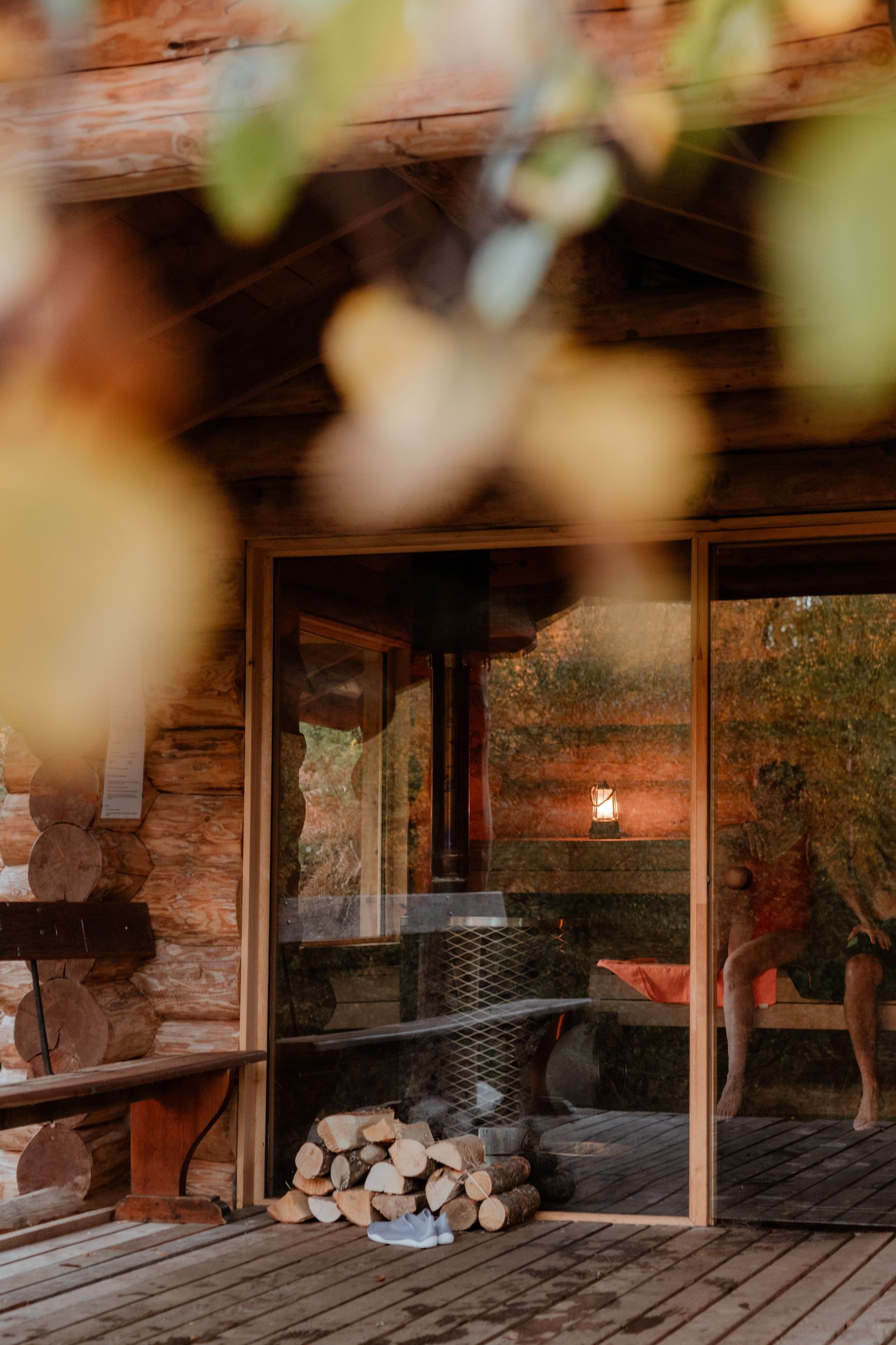A person paddles a green kayak on calm water past a rocky, tree-lined coastline under a clear blue sky.