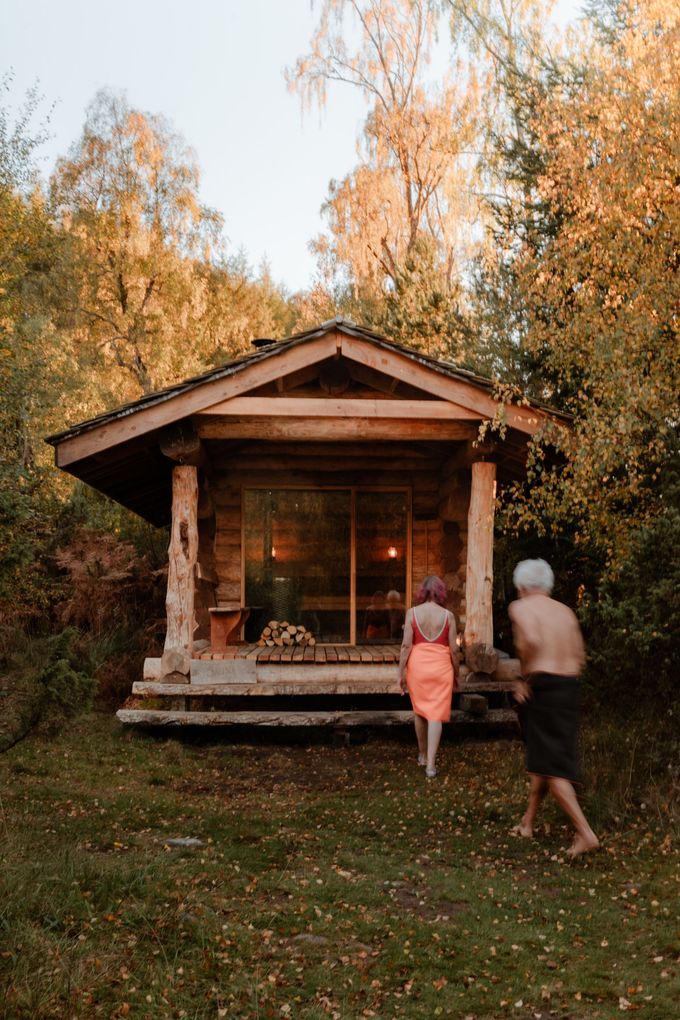 Lighthouse on a rocky island at sunset, against a sea and mountain backdrop.