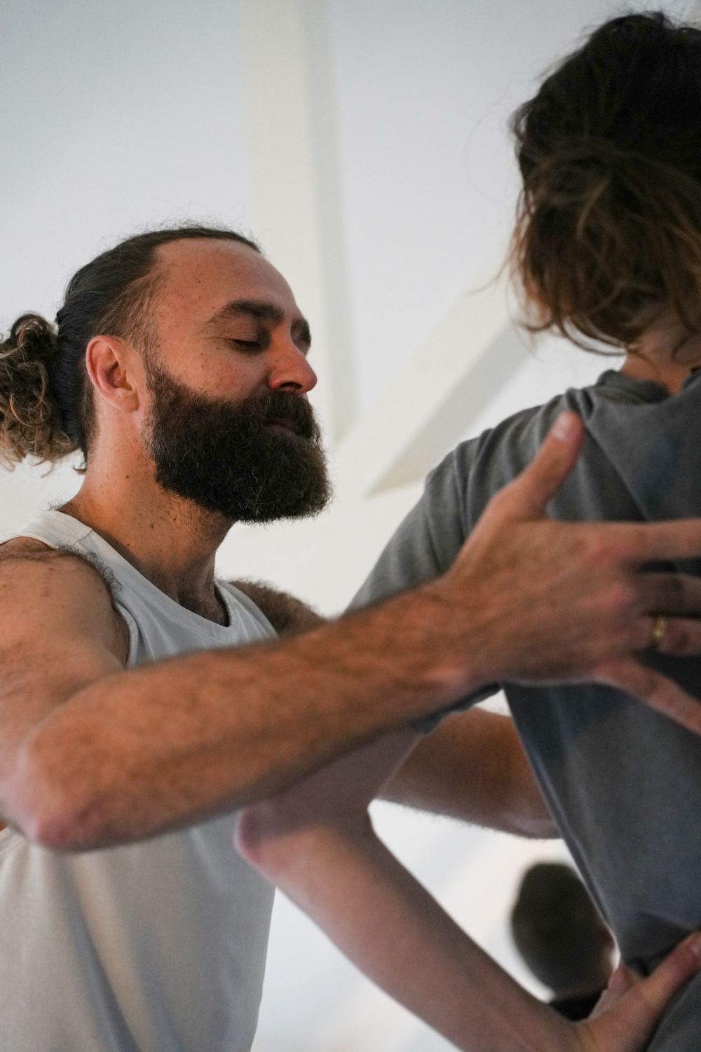 A man helping a lady in yoga