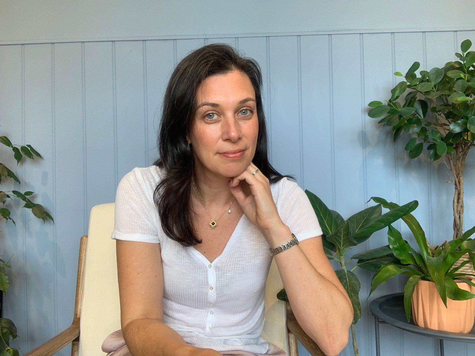 Kimberly Parsons sits in a chair, smiling. Wearing a white shirt.