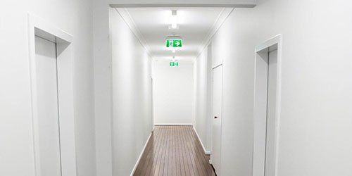 A long hallway with white walls and wooden floors in a building.