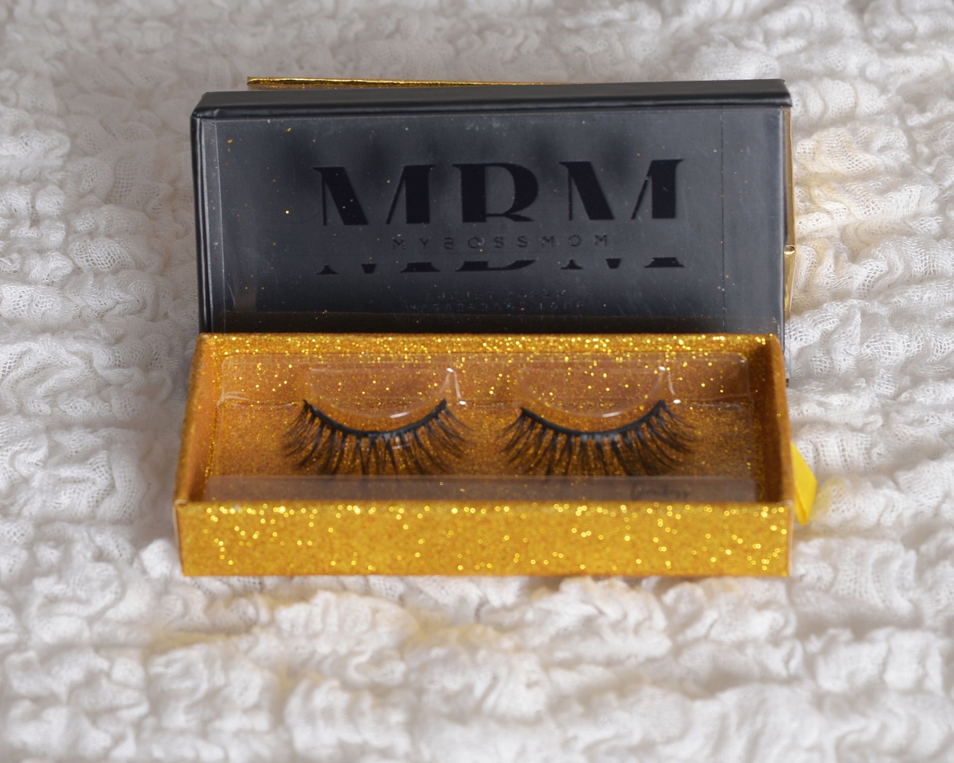 A pair of mdm eyelashes in a gold box