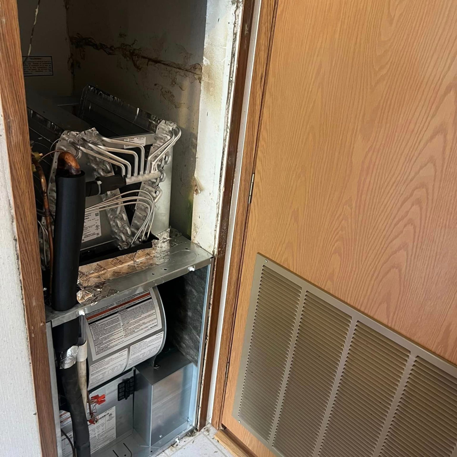A broken air conditioner is sitting inside of a wooden cabinet.