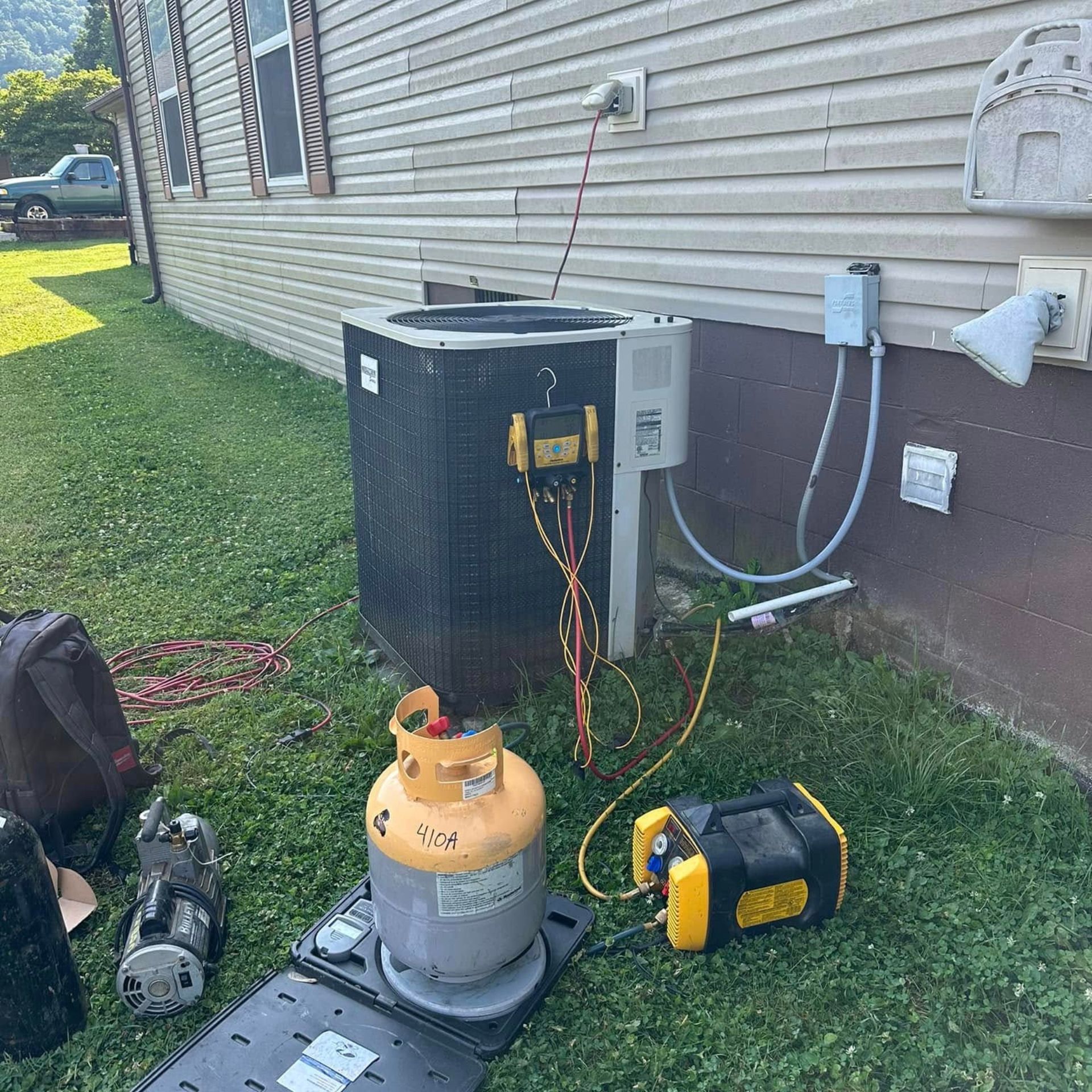 An air conditioner is being serviced outside of a house.