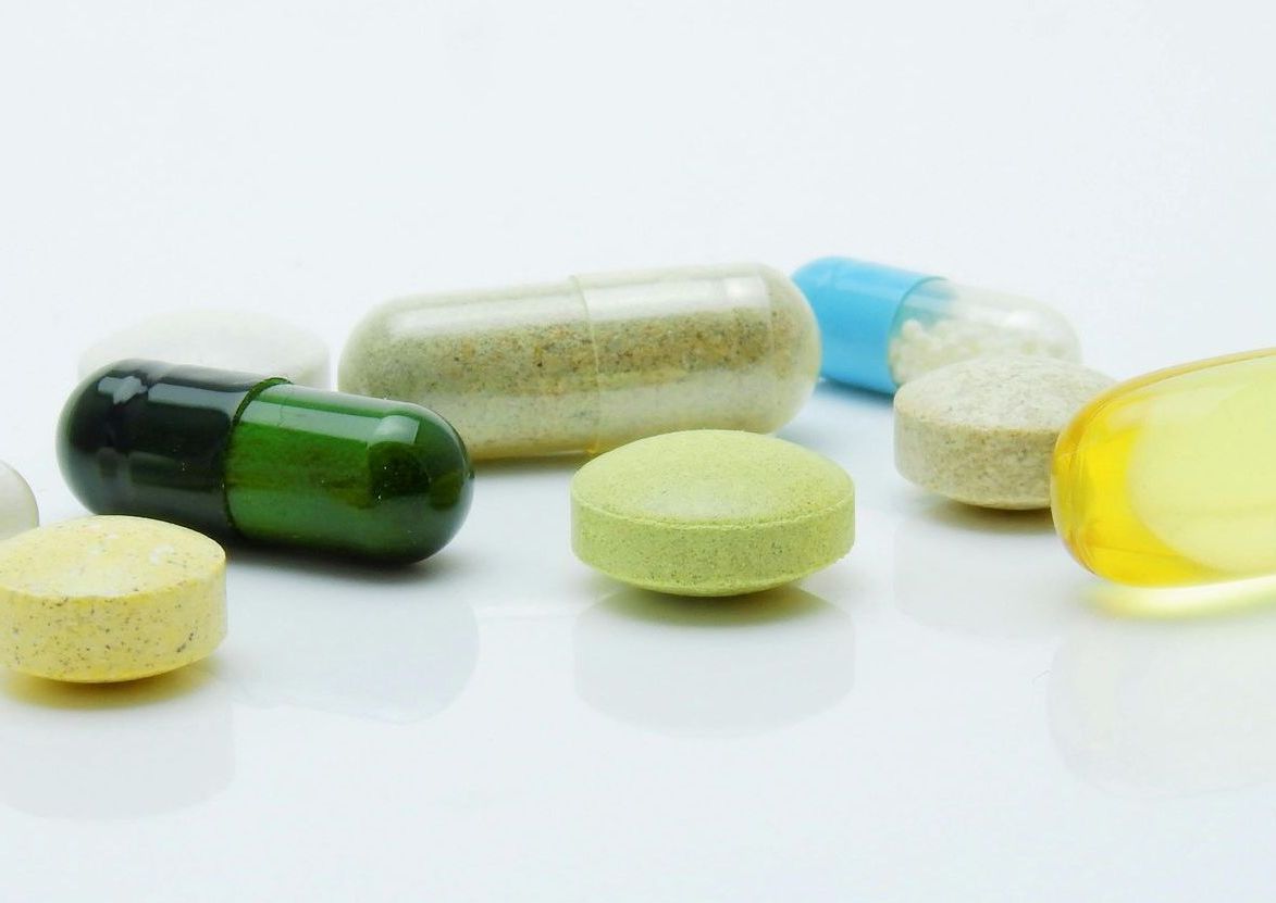 A variety of pills and capsules on a white surface