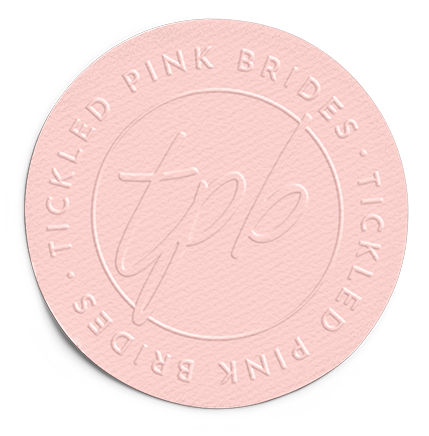 A circular pale pink emblem with a textured surface, featuring the embossed text
