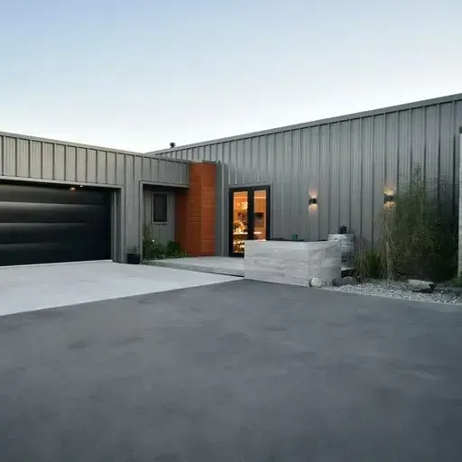 Modern gray corrugated metal home with black garage door, front entrance, and concrete driveway.
