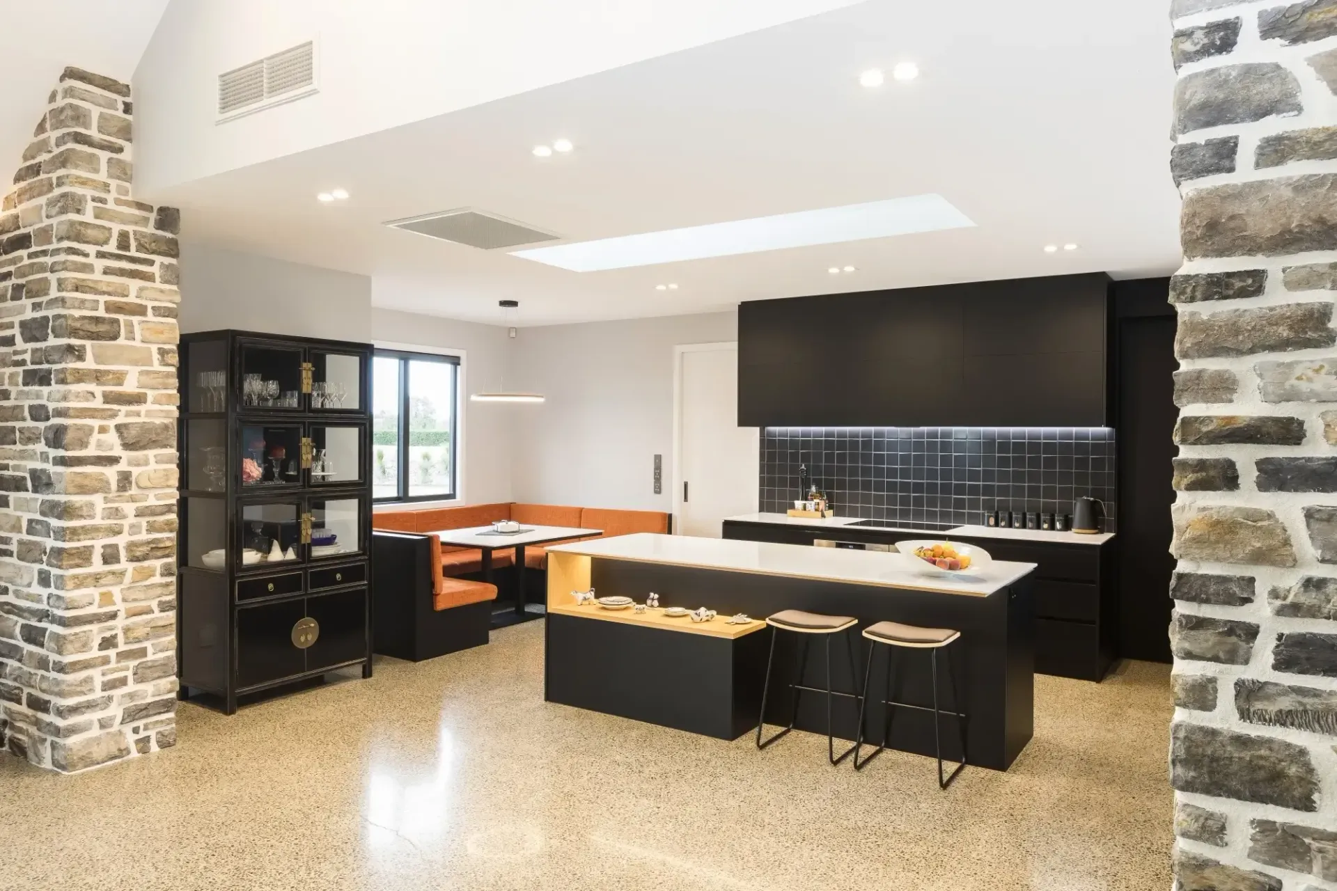 Modern kitchen with black cabinetry, stone accents, and a central island with stools.