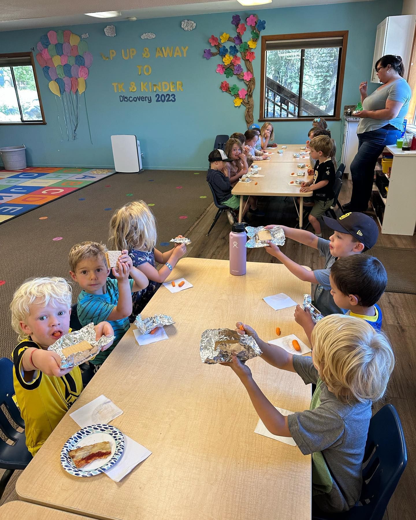 A group of children are sitting at a table eating food.