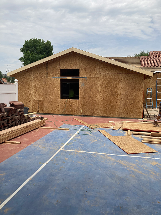 Construction of a new building; OSB siding on a blue-painted court. Cloudy sky.